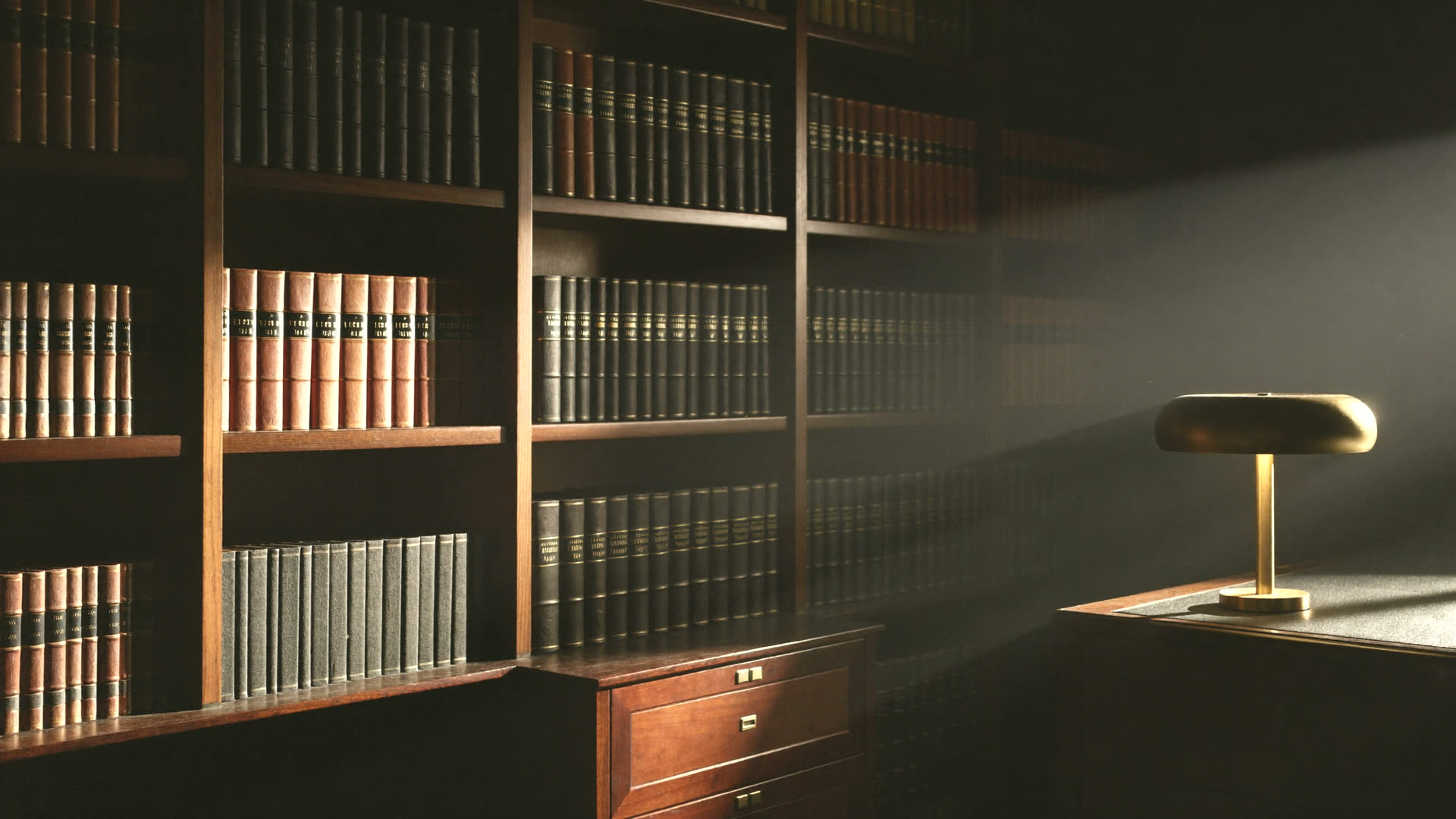 Biblioteca jurídica con volúmenes encuadernados iluminados por una lámpara, base doctrinaria del trabajo de Iriarte & Solar